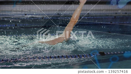 Executing backstroke swimmer propelling through lanes in training pool, with swim cap and swimsuit Executing backstroke swimmer propelling through lanes in training pool, with swim cap and swimsuit 139257416