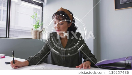 Writing woman at desk by window, using black pen, accessories and plant under shopping cart overlay 139257486