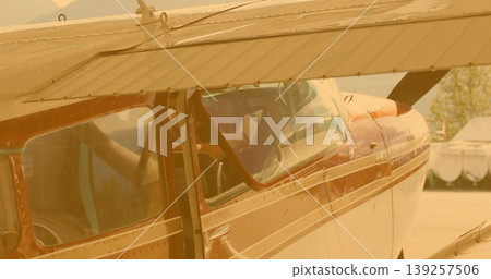 Parking single-engine prop plane under wing shadow on airfield apron, with pilot checking tablet Parking single-engine prop plane under wing shadow on airfield apron, with pilot checking tablet 139257506