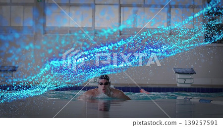 Surfacing male swimmer cutting through lap pool, wearing swim goggles, with glowing blue particles Surfacing male swimmer cutting through lap pool, wearing swim goggles, with glowing blue particles 139257591