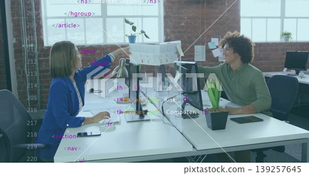 Reaching businesswoman passing printed chart to colleague over divider in office, with monitors Reaching businesswoman passing printed chart to colleague over divider in office, with monitors 139257645