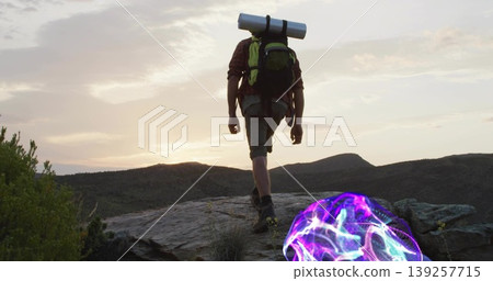 Climbing hiker wearing flannel shirt and shorts on mountain ridge dusk, green backpack, glowing orb Climbing hiker wearing flannel shirt and shorts on mountain ridge dusk, green backpack, glowing orb 139257715