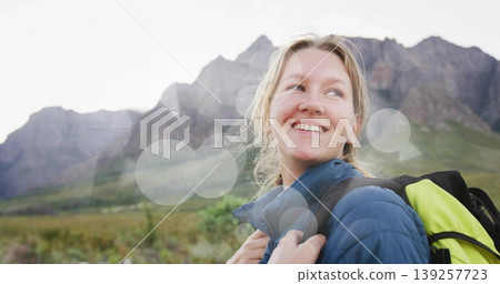 Smiling hiker holding neon yellow-green backpack, gazing in mountains with blue jacket, copy space Smiling hiker holding neon yellow-green backpack, gazing in mountains with blue jacket, copy space 139257723