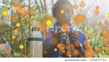 Holding camping mug, man wearing blue vest sipping hot drink in forest clearing, with steel thermos Holding camping mug, man wearing blue vest sipping hot drink in forest clearing, with steel thermos 139257731