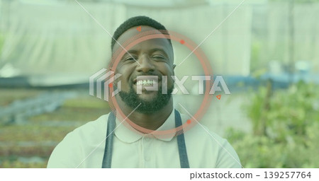 Smiling mid adult male gardener tending seedling trays in greenhouse, with apron and metal benches Smiling mid adult male gardener tending seedling trays in greenhouse, with apron and metal benches 139257764