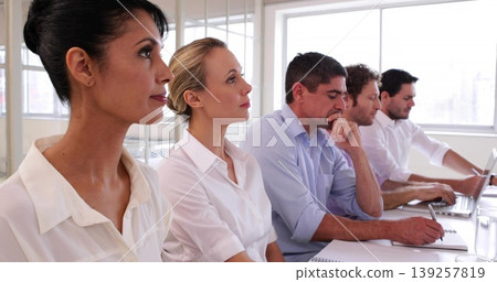 Sitting five professionals in business casual at office meeting room, with notebooks and laptops Sitting five professionals in business casual at office meeting room, with notebooks and laptops 139257819