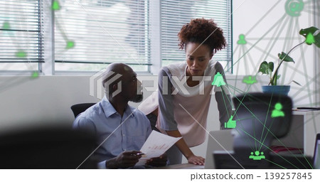 Reviewing senior colleagues in business attire analyzing chart data at office desk, with laptop Reviewing senior colleagues in business attire analyzing chart data at office desk, with laptop 139257845