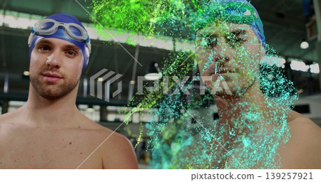 Standing two swimmers wearing blue and green caps and goggles at pool, with digital particles Standing two swimmers wearing blue and green caps and goggles at pool, with digital particles 139257921