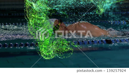 Gliding male swimmer wearing cap and goggles past lane ropes in pool, with neon digital particles Gliding male swimmer wearing cap and goggles past lane ropes in pool, with neon digital particles 139257924