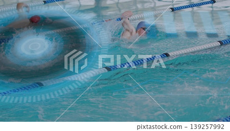 Male swimmers racing side by side in aquatic center pool, with silicone caps and goggles Male swimmers racing side by side in aquatic center pool, with silicone caps and goggles 139257992