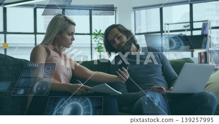Reviewing data on laptop, professionals working in office lounge, with digital interface Reviewing data on laptop, professionals working in office lounge, with digital interface 139257995