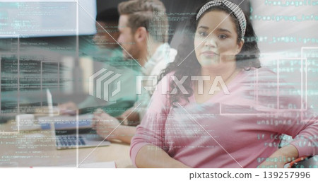 Woman wearing pink sweater and headband reviewing projected code in office, with laptops Woman wearing pink sweater and headband reviewing projected code in office, with laptops 139257996