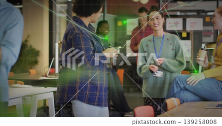 Gesturing woman in green sweater speaking in open-plan office, with coffee cups and sticky notes Gesturing woman in green sweater speaking in open-plan office, with coffee cups and sticky notes 139258008