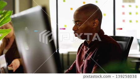 Reviewing colleague with burgundy shirt viewing monitor in office, with sticky notes, copy space Reviewing colleague with burgundy shirt viewing monitor in office, with sticky notes, copy space 139258038