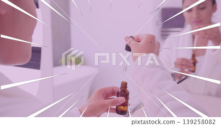 Using dropper woman in bathrobe dispensing liquid from amber bottle at vanity, reflecting in mirror 139258082