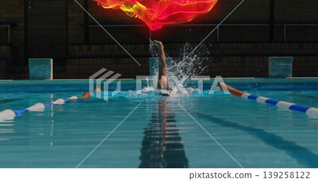 Backstroking male swimmer with cap, goggles among lane dividers in pool showing floating red light Backstroking male swimmer with cap, goggles among lane dividers in pool showing floating red light 139258122