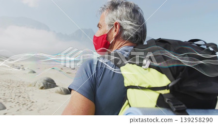 Standing man wearing red mask, blue shirt on beach with backpack and sleeping mat, copy space Standing man wearing red mask, blue shirt on beach with backpack and sleeping mat, copy space 139258290