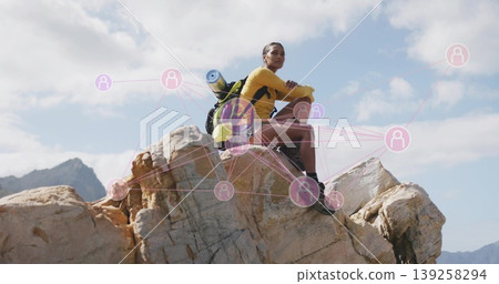 Resting hiker wearing yellow top and pink shorts on rocky summit, with green backpack and boots Resting hiker wearing yellow top and pink shorts on rocky summit, with green backpack and boots 139258294
