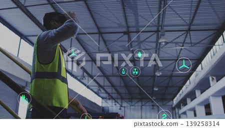 Scanning engineer viewing floating icons on steel stairs in warehouse, with safety vest, copy space Scanning engineer viewing floating icons on steel stairs in warehouse, with safety vest, copy space 139258314