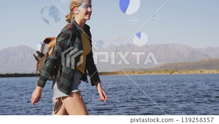 walking hiker wearing plaid shirt carrying tan backpack and metal bottle on lakeshore, copy space walking hiker wearing plaid shirt carrying tan backpack and metal bottle on lakeshore, copy space 139258357