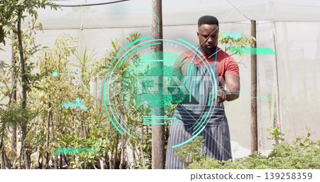 Inspecting African American gardener tending plants in plant nursery with smartwatch AR, copy space Inspecting African American gardener tending plants in plant nursery with smartwatch AR, copy space 139258359