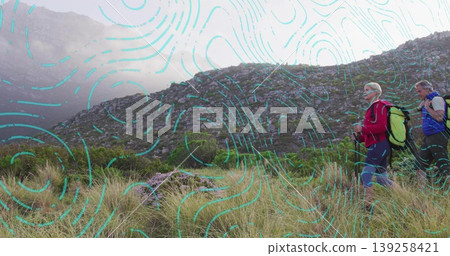 Mature hikers climbing grassy slope at base of rocky hillside, with backpacks and poles, copy space Mature hikers climbing grassy slope at base of rocky hillside, with backpacks and poles, copy space 139258421