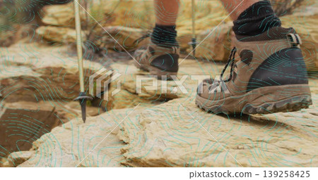 Pressing right hiking boot on sandstone outcrop, showing second boot and pole sinking, copy space 139258425
