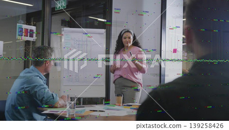 Presenting adult woman in business attire explaining graphs at flip chart in meeting room, charts Presenting adult woman in business attire explaining graphs at flip chart in meeting room, charts 139258426
