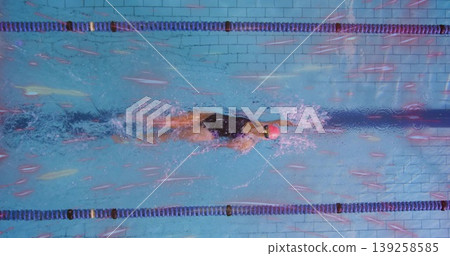 Gliding swimmer wearing black suit, red cap, goggles in pool lane, with blue dividers, tiled floor Gliding swimmer wearing black suit, red cap, goggles in pool lane, with blue dividers, tiled floor 139258585