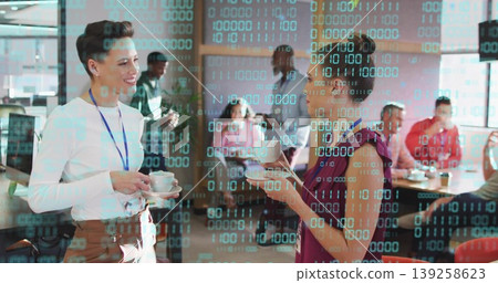 Chatting two women wearing business attire in open lounge, holding coffee cups under binary overlay 139258623
