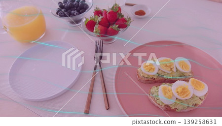 Displaying avocado toast topped with egg on pink plate at dining table, juice, berries, copy space Displaying avocado toast topped with egg on pink plate at dining table, juice, berries, copy space 139258631
