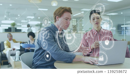 Collaborating coworkers typing, pointing at laptop at round table in office lounge, with white mug Collaborating coworkers typing, pointing at laptop at round table in office lounge, with white mug 139258672