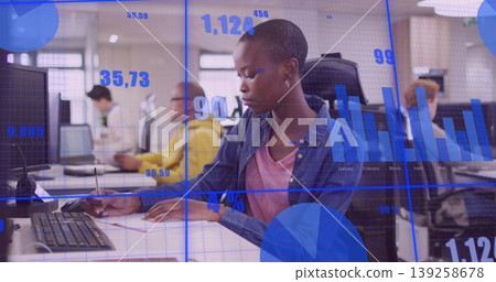 Writing woman in denim shirt taking notes at office workspace, with notebook monitor data overlay Writing woman in denim shirt taking notes at office workspace, with notebook monitor data overlay 139258678