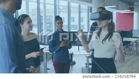 Showing woman wearing virtual reality headset gesturing in open office, with tablet, copy space Showing woman wearing virtual reality headset gesturing in open office, with tablet, copy space 139258764