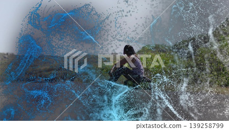 Squatting Indian woman in camo pants gazing right on hillside with blue white particle streams Squatting Indian woman in camo pants gazing right on hillside with blue white particle streams 139258799