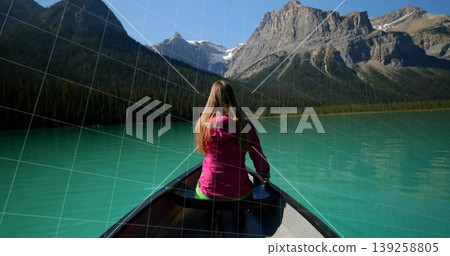 Looking woman wearing bright pink jacket sitting in canoe at turquoise mountain lake, with paddle Looking woman wearing bright pink jacket sitting in canoe at turquoise mountain lake, with paddle 139258805