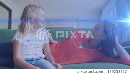 Mother and daughter reclining on green couch in living room, sharing fond gaze under sunlight flare Mother and daughter reclining on green couch in living room, sharing fond gaze under sunlight flare 139258812