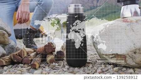 Standing vacuum flask on riverbank, with hiker preparing firewood by percolator, map overlay Standing vacuum flask on riverbank, with hiker preparing firewood by percolator, map overlay 139258912
