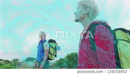Walking couple wearing red jacket, blue vest on mountainous hillside trail, with backpacks 139258932