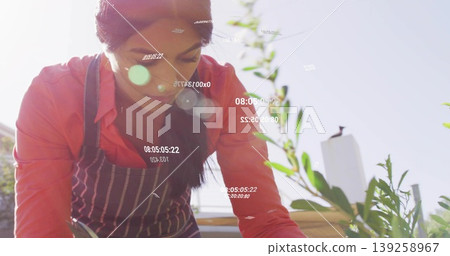 Leaning woman wearing apron inspecting green plants in planter on rooftop, with floating timestamps Leaning woman wearing apron inspecting green plants in planter on rooftop, with floating timestamps 139258967