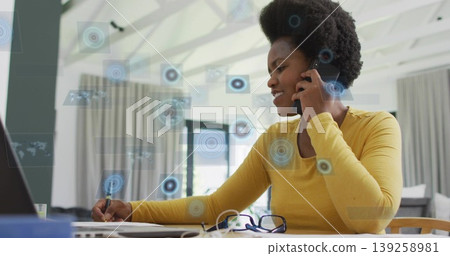 Talking woman holding smartphone to ear, writing on papers at desk, with laptop, pen, copy space Talking woman holding smartphone to ear, writing on papers at desk, with laptop, pen, copy space 139258981