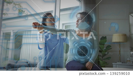 Physical therapist in scrubs assisting patient performing arm stretch at home, with digital overlay Physical therapist in scrubs assisting patient performing arm stretch at home, with digital overlay 139259010
