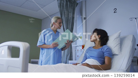 Reviewing nurse wearing blue scrubs explaining chart to patient in hospital room with IV stand Reviewing nurse wearing blue scrubs explaining chart to patient in hospital room with IV stand 139259014