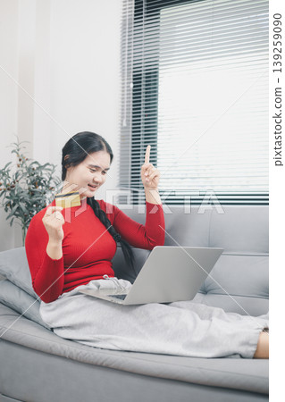 Young Asian woman celebrating online shopping success with laptop and credit card at home, pointing up for discount offer, cashback deal, ecommerce payment and digital purchase concept Young Asian woman celebrating online shopping success with laptop and credit card at home, pointing up for discount offer, cashback deal, ecommerce payment and digital purchase concept 139259090