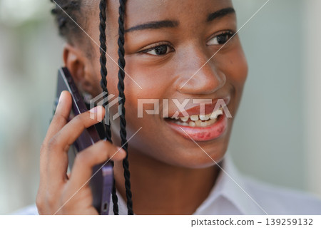 Young African professional woman writing on tablet with stylus while standing outdoors, concept of digital note taking, planning, remote work and modern paperless productivity. 139259132