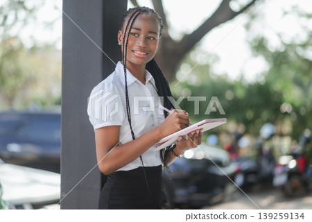 Young African woman using tablet and stylus outdoors while looking away, concept of digital planning, mobile workflow, creative productivity and modern flexible work lifestyle. 139259134