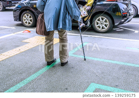 Cityscape of Yokohama, Japan: Aging society...An elderly woman with a cane (wearing a mask) waiting for a taxi at a taxi stand in Yokohama City. Cityscape of Yokohama, Japan: Aging society...An elderly woman with a cane (wearing a mask) waiting for a taxi at a taxi stand in Yokohama City. 139259175