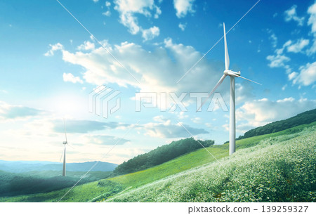 Two wind turbines rotate on green hills. The landscape features a clear blue sky filled with clouds. The sun shines bright, highlighting the green fields and trees nearby. Two wind turbines rotate on green hills. The landscape features a clear blue sky filled with clouds. The sun shines bright, highlighting the green fields and trees nearby. 139259327