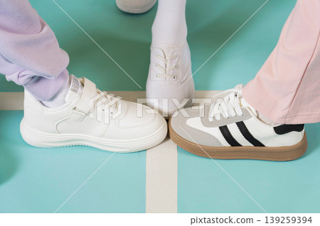 Three pairs of shoes meet on a bright floor. Each person wears different styles of shoes. The setting looks fun and casual for a social moment among friends. Three pairs of shoes meet on a bright floor. Each person wears different styles of shoes. The setting looks fun and casual for a social moment among friends. 139259394