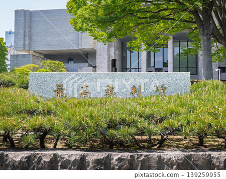 A plaque bearing the name "Supreme Court" stands beyond a stone wall and shrubbery, representing the Japanese judicial system. A plaque bearing the name "Supreme Court" stands beyond a stone wall and shrubbery, representing the Japanese judicial system. 139259955